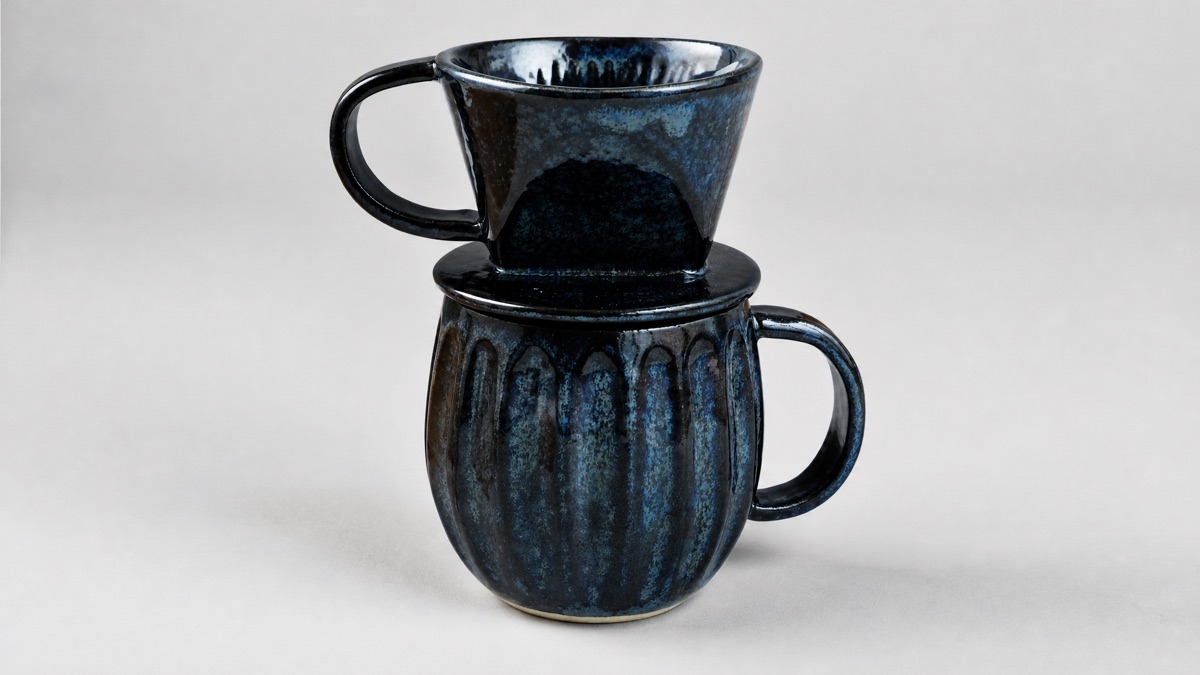 Asayu Japan dark navy ceramic pour over dripper sitting on a matching ribbed ceramic mug on a plain neutral background